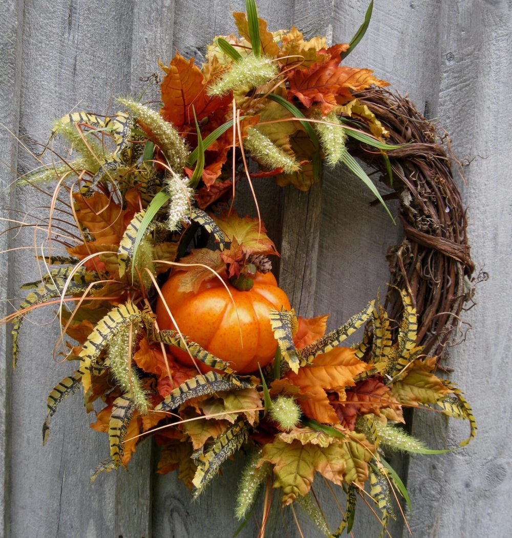A wreath with leaves and a pumpkin on it
