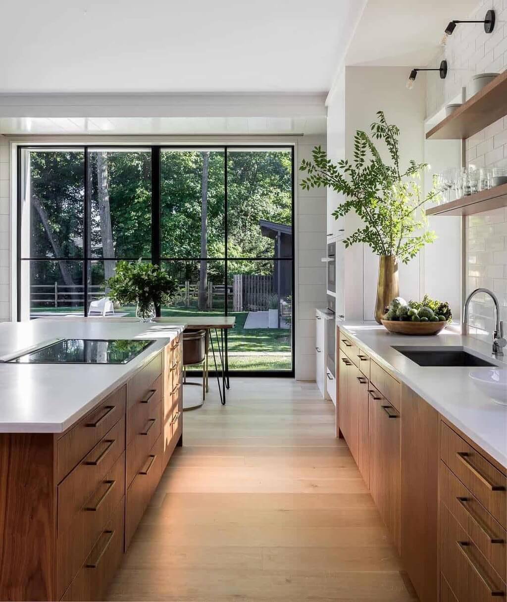 A modern kitchen with large windows and wooden cabinets.