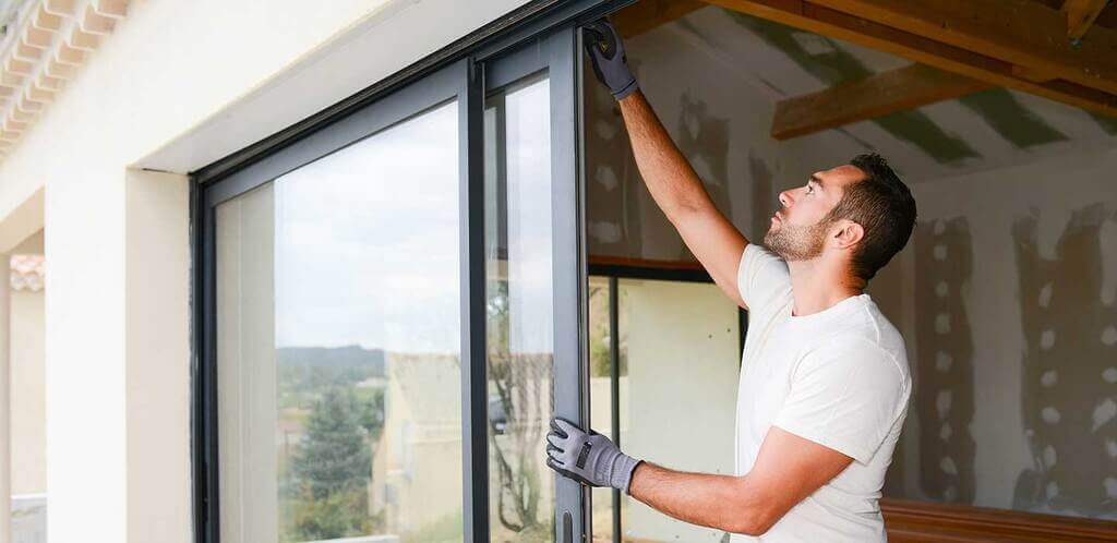 A man installing a sliding glass door in a house.