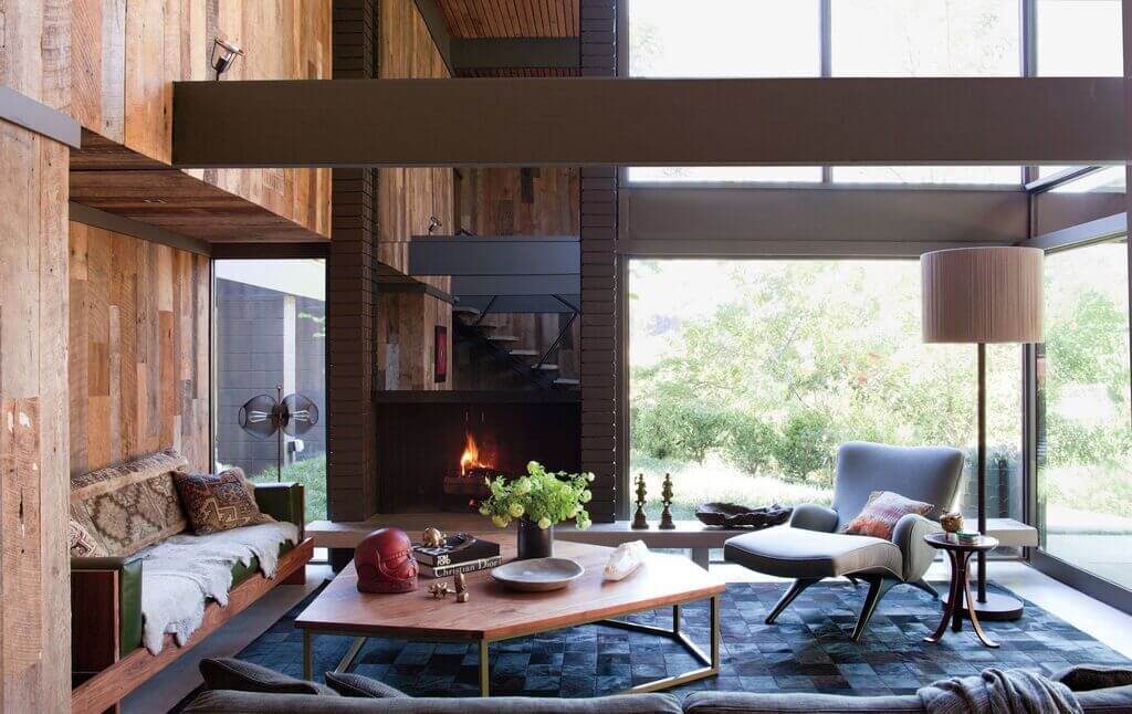 A living room with wood walls and a fireplace.