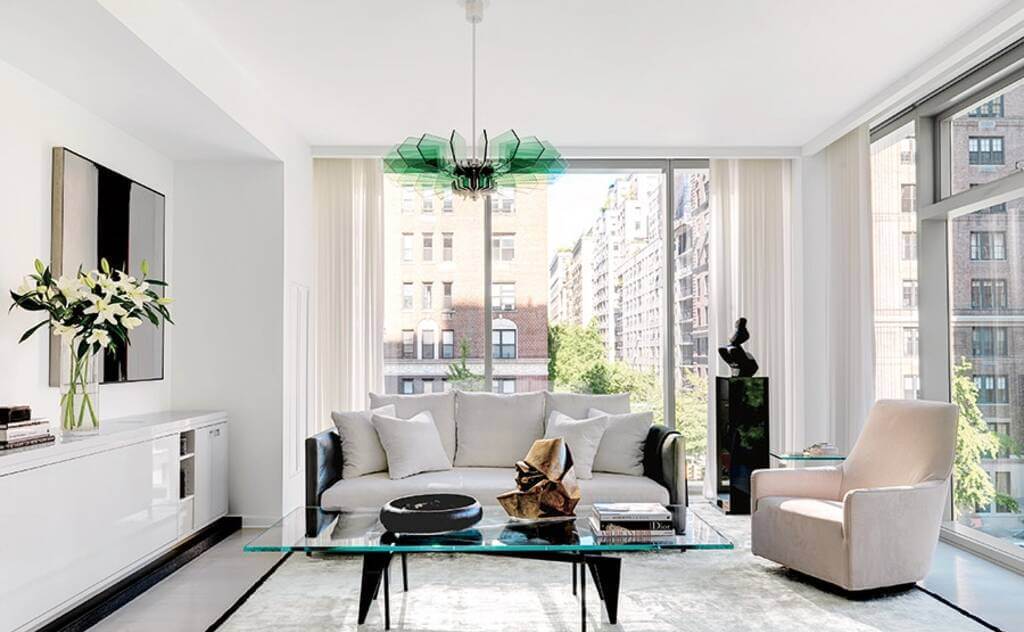 A white living room with large windows and a glass coffee table.