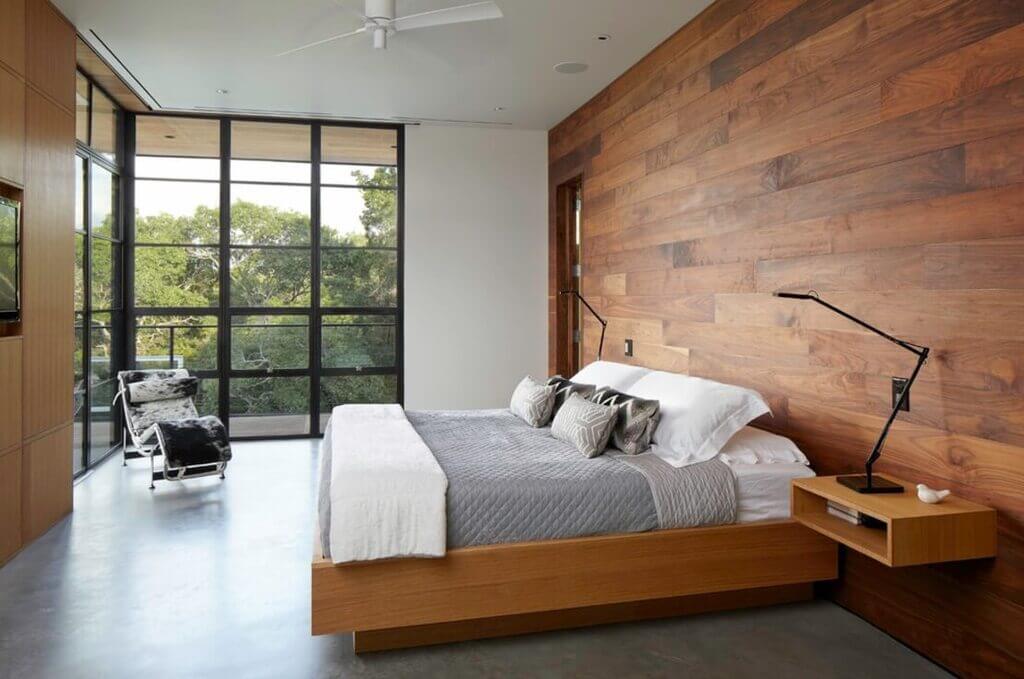 A modern bedroom with wood walls and a bed.