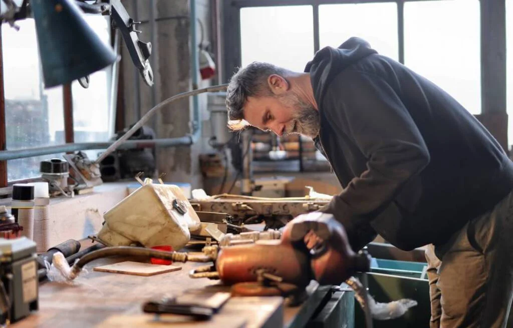 A man working on a piece of wood in a works،p
