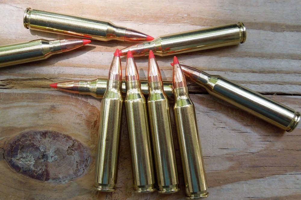 A bunch of bullet shells sitting on top of a wooden table
