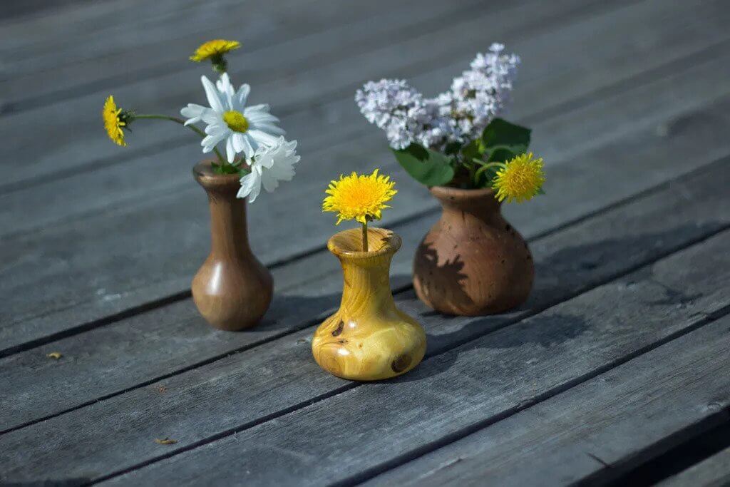 Three vases with flowers in them sitting on a wooden table
