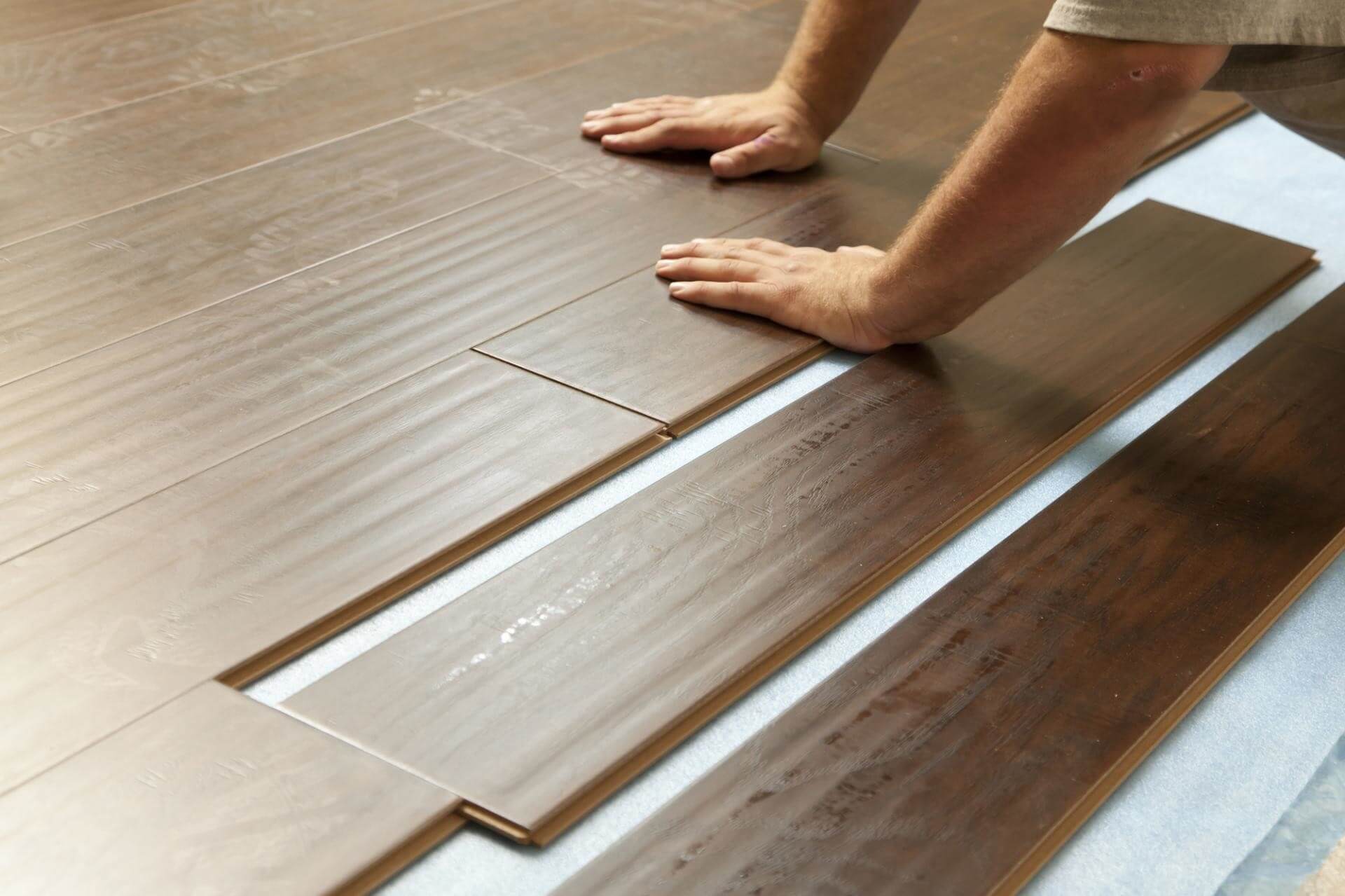 A person laying on a wooden floor with their feet on the floor
