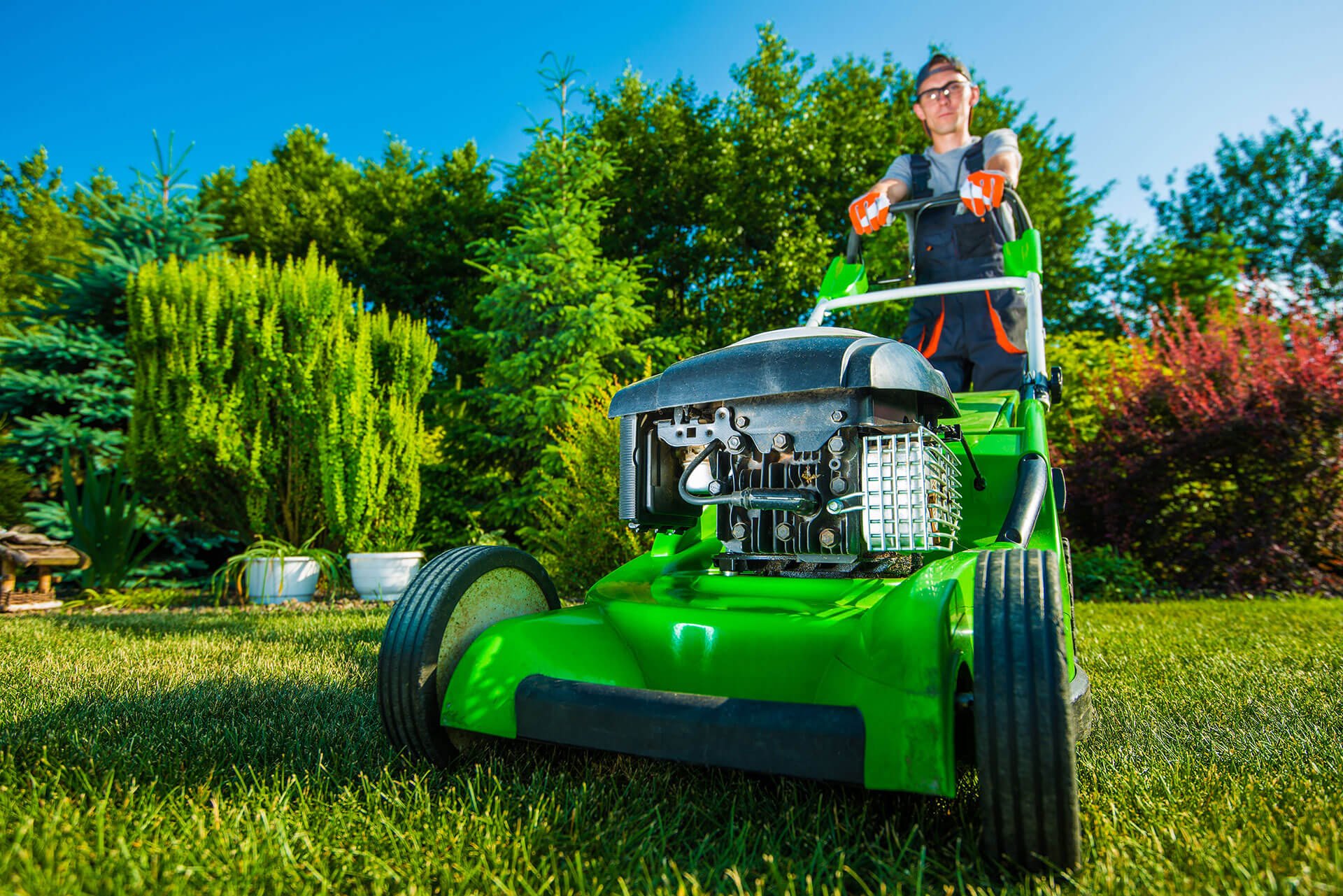 A man mowing the grass with a green lawn mower
