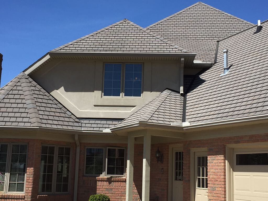 A brick house with a gray roof and two garages
