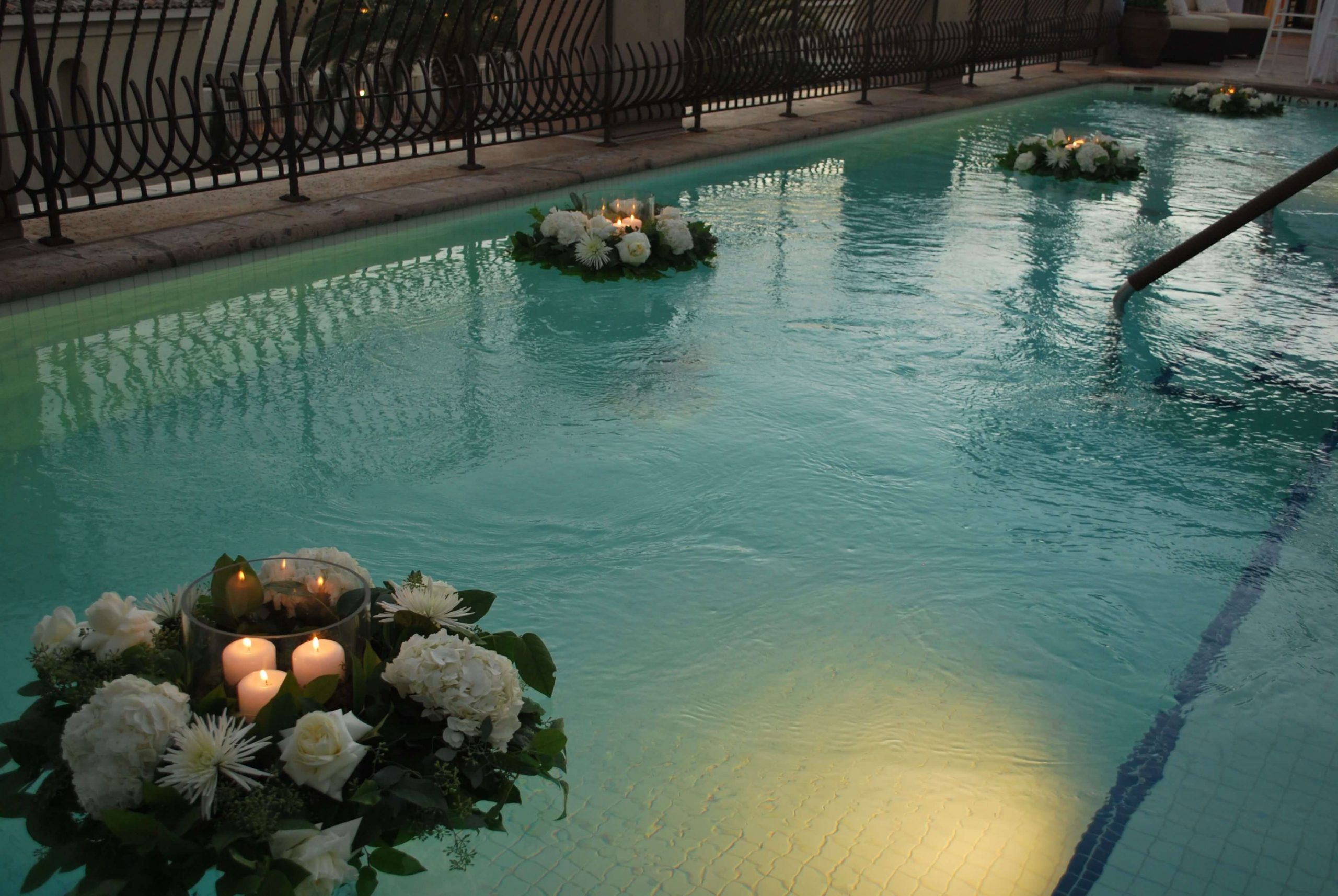 A pool with candles and flowers in it
