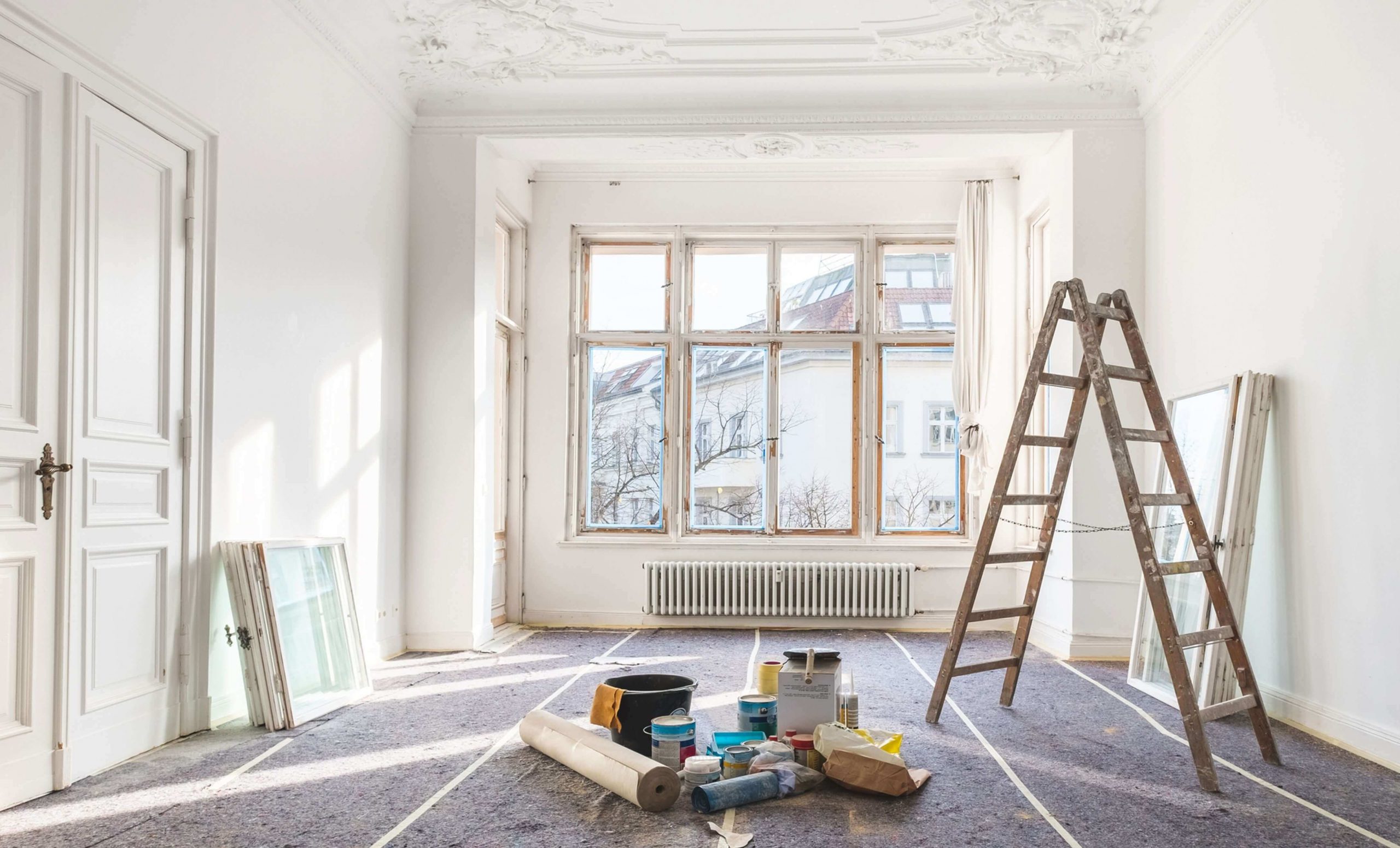 A room with a ladder, paint cans and a ladder
