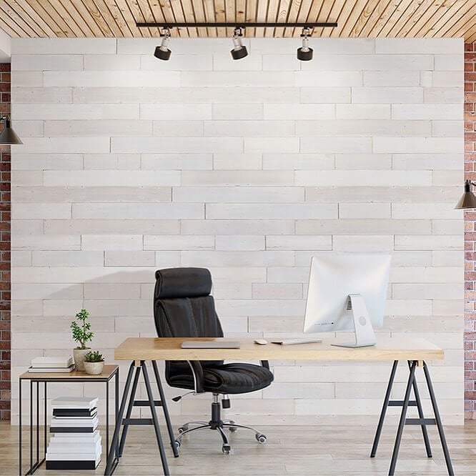 A desk with a computer on it in front of a brick wall
