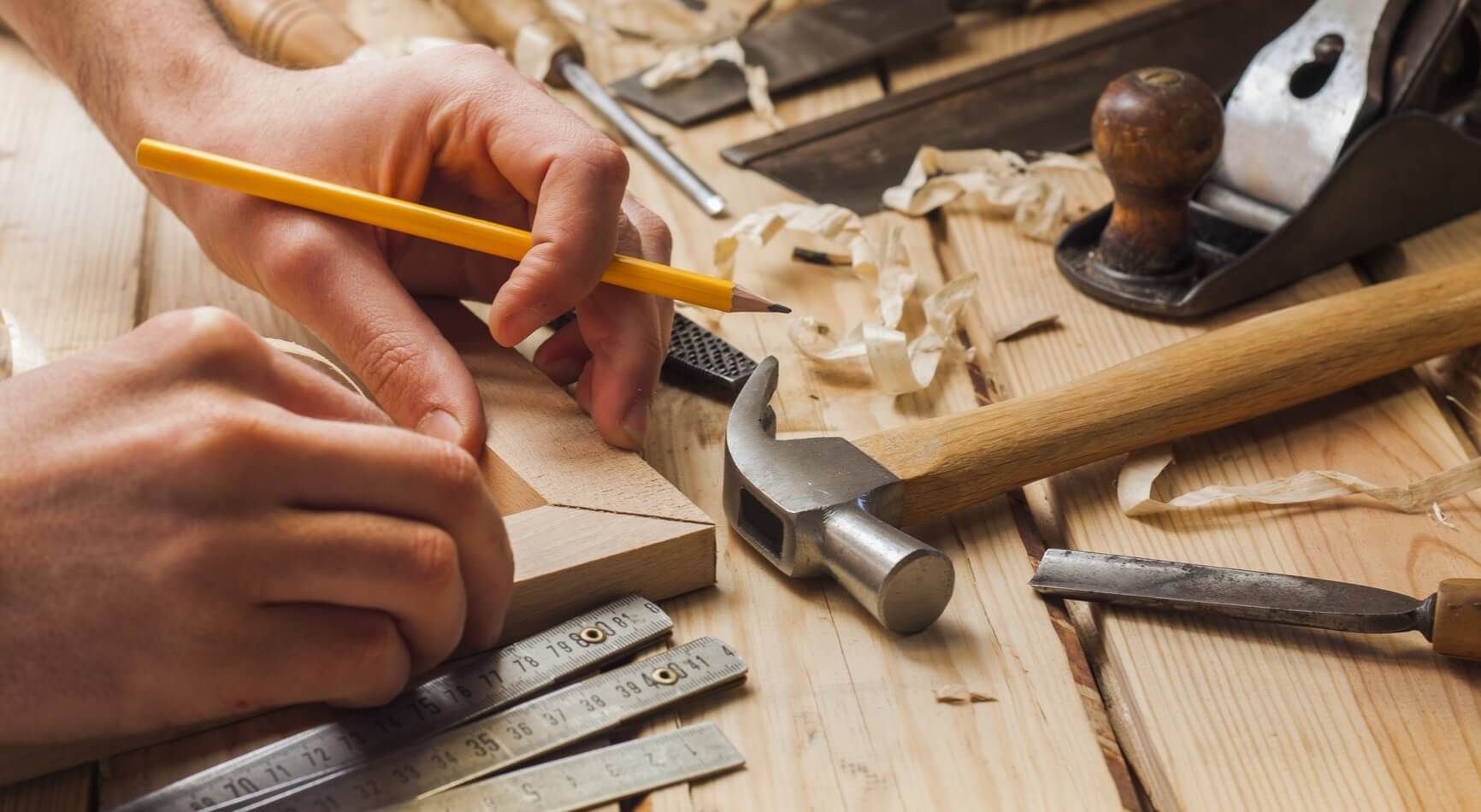 A man working on a piece of wood with a pencil
