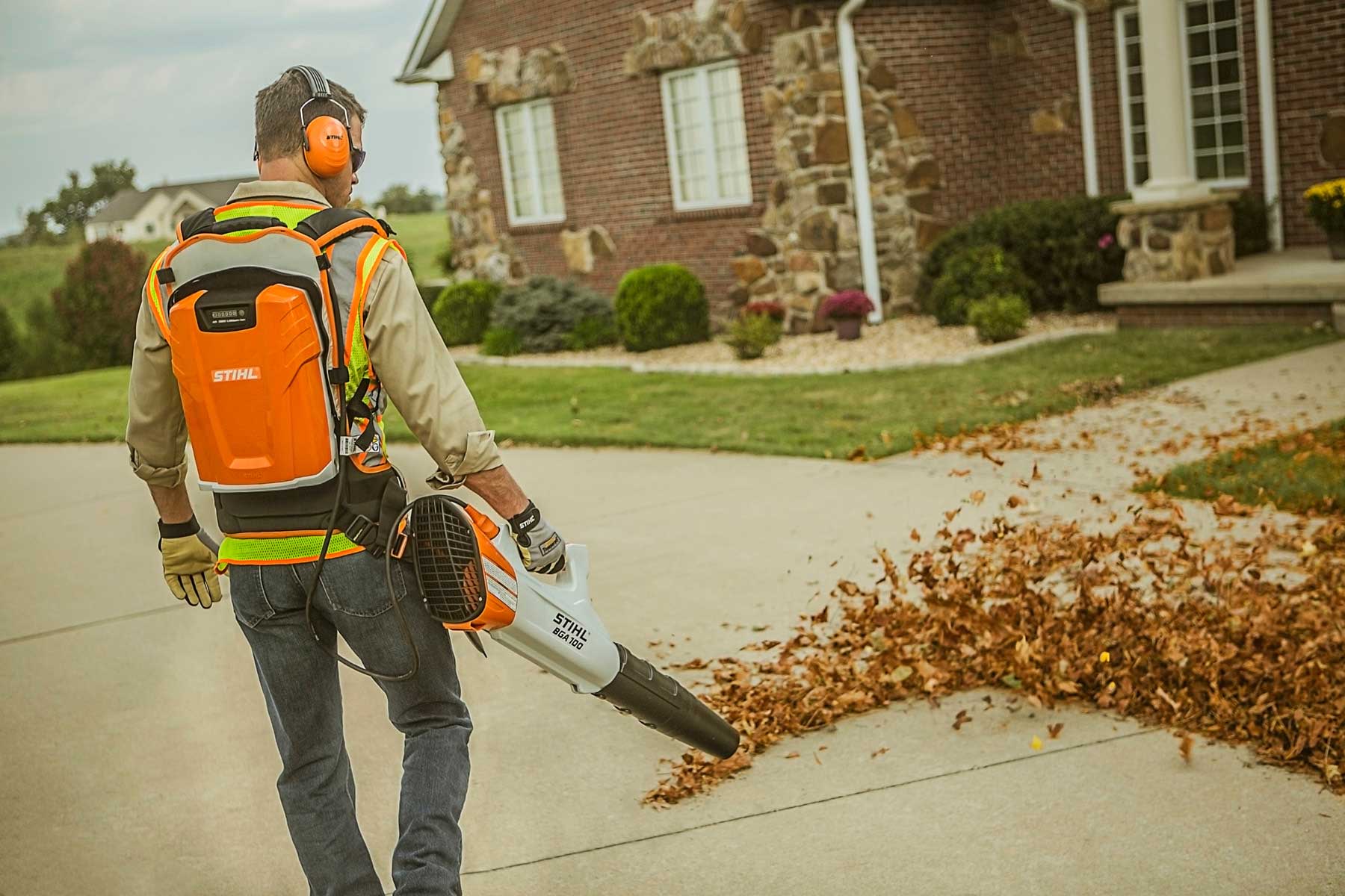 A man with a Leaf Blower in front of a house

