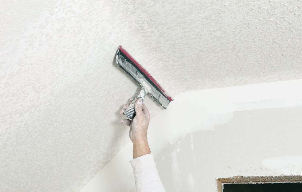 A person using a paint roller to paint a wall
