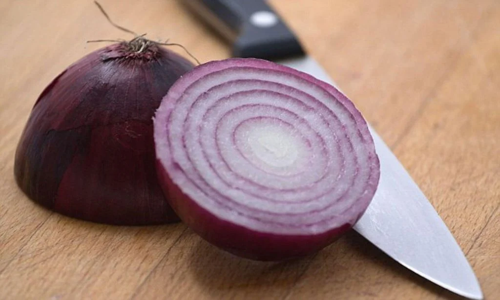 An onion and a knife on a cutting board
