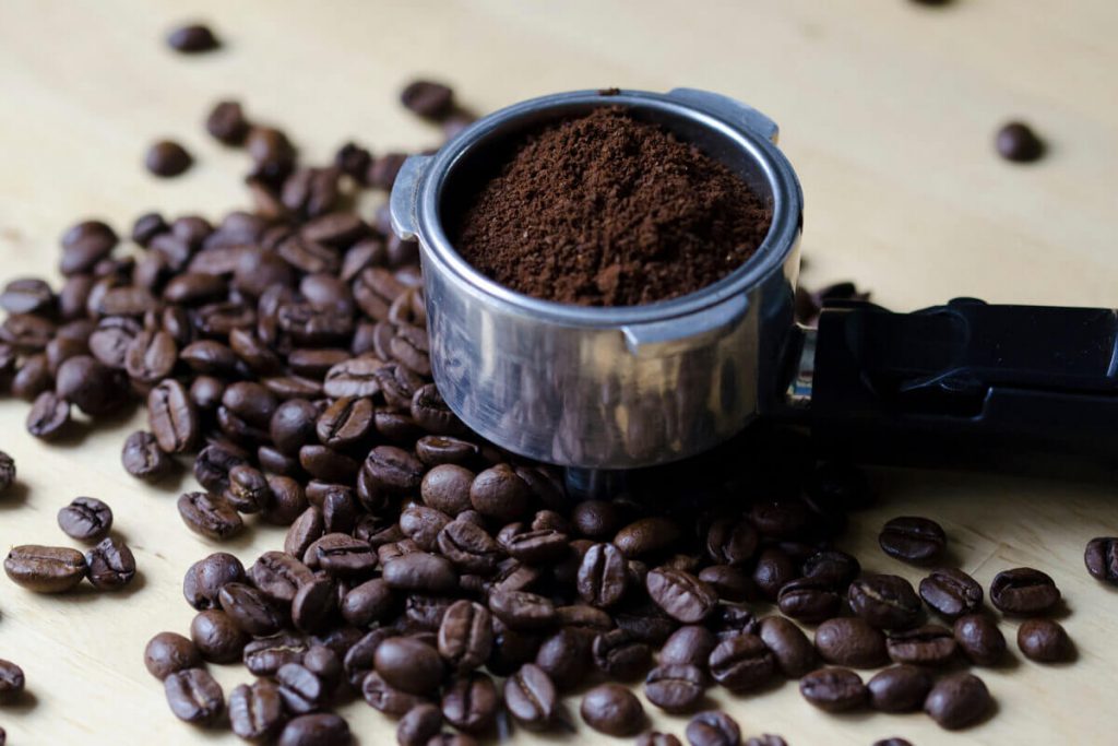 A grinder filled with coffee beans on top of a wooden table
