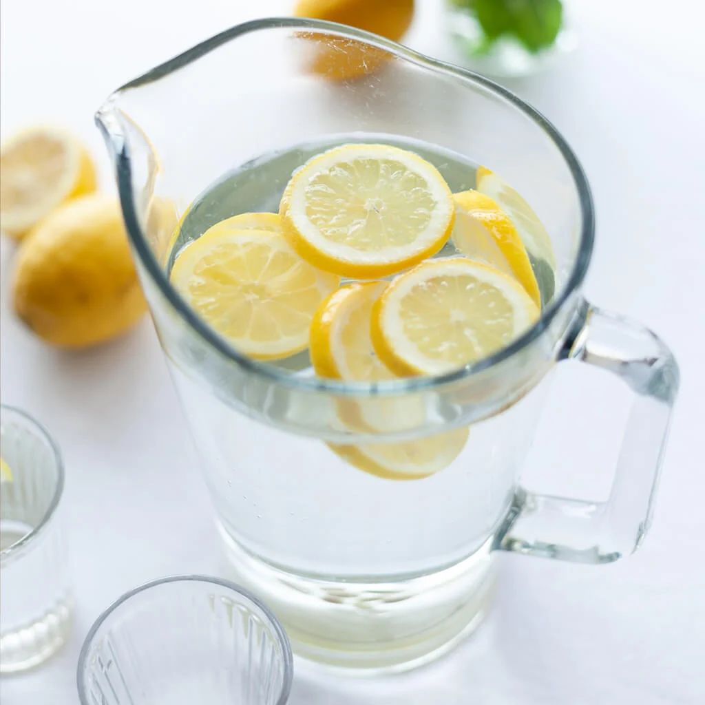 A pitcher of water with lemon slices in it
