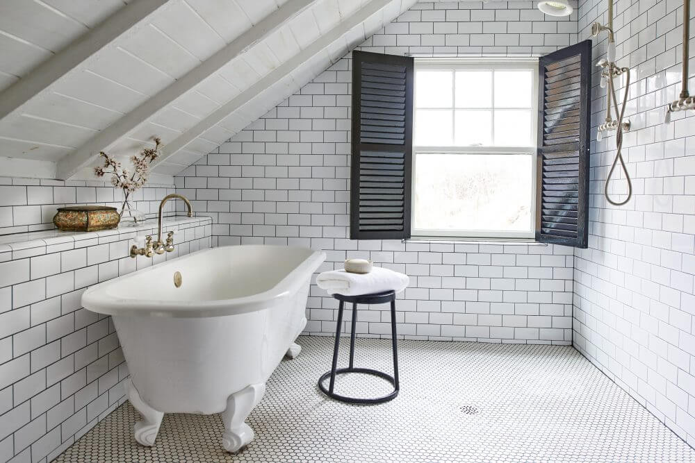A white bath tub sitting under a window in a bathroom
