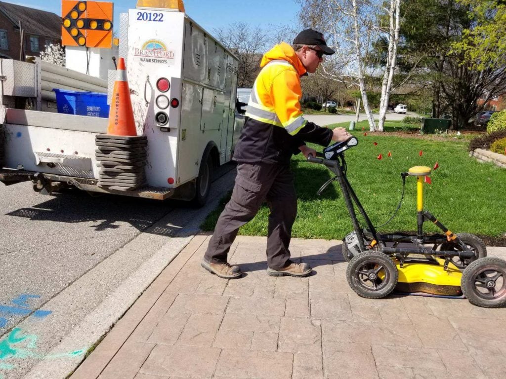 A man pushing a push  Ground Penetrating Radar  on a sidewalk
