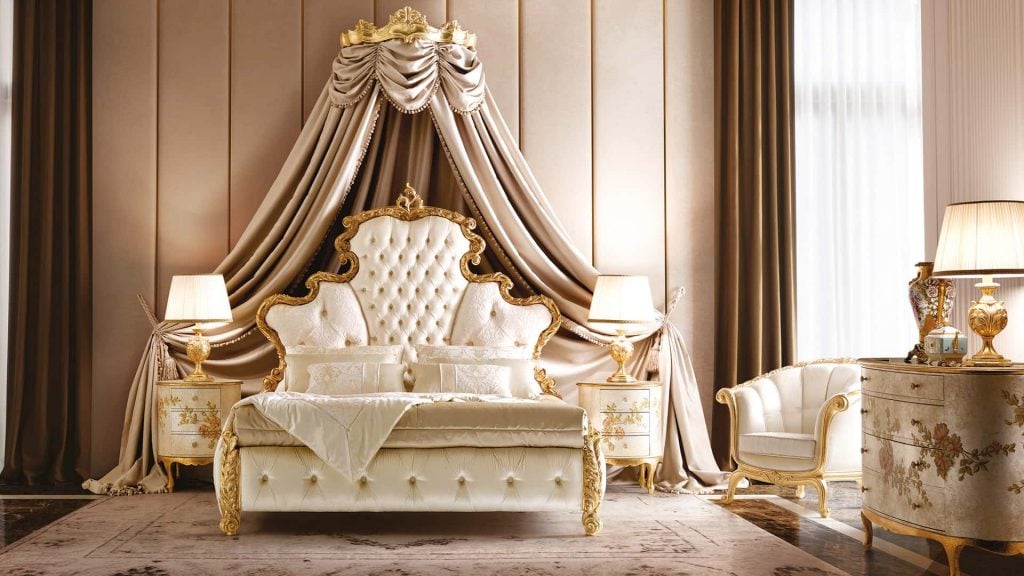 A fancy bedroom with a white couch and gold furniture
