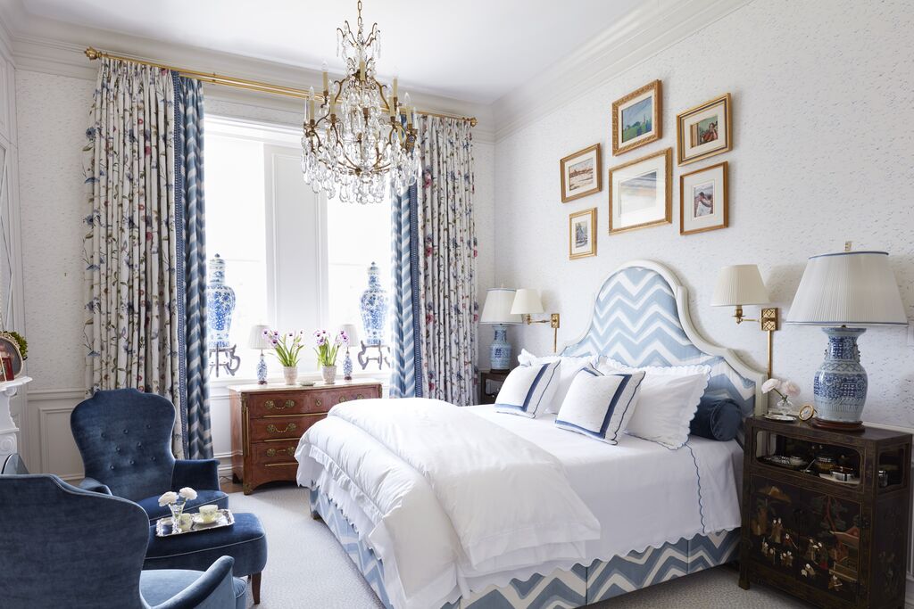 A bed room with a neatly made bed and a chandelier
