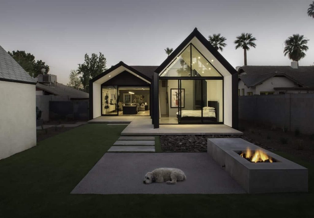 A dog laying on the ground in front of a house
