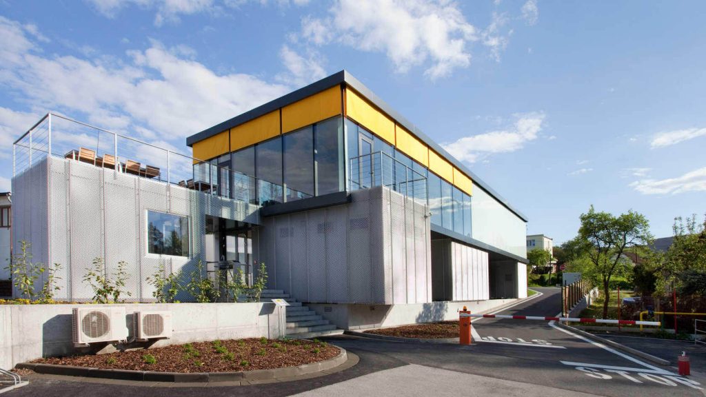 A modern building with a yellow roof and glass windows
