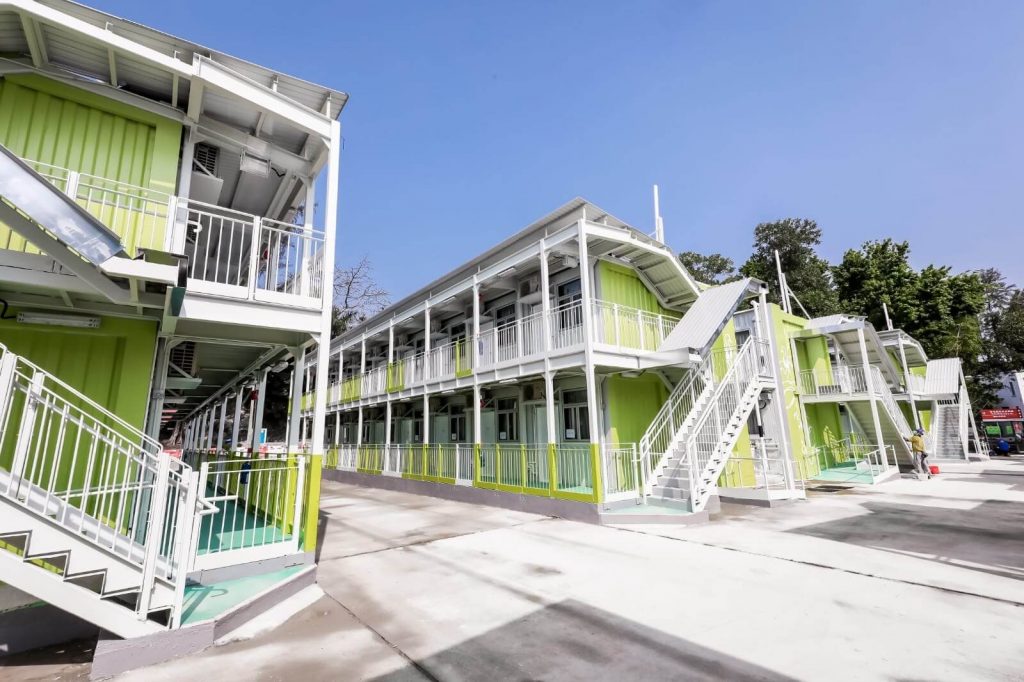 A row of green buildings with white balconies
