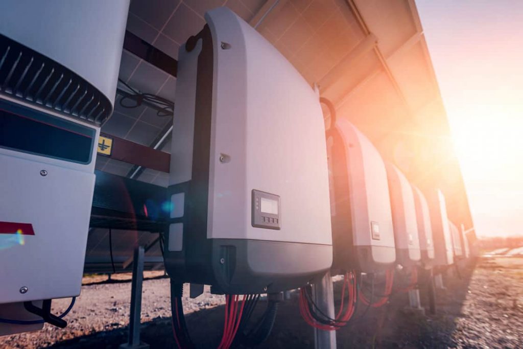 A row of white electrical equipment sitting on top of a field
