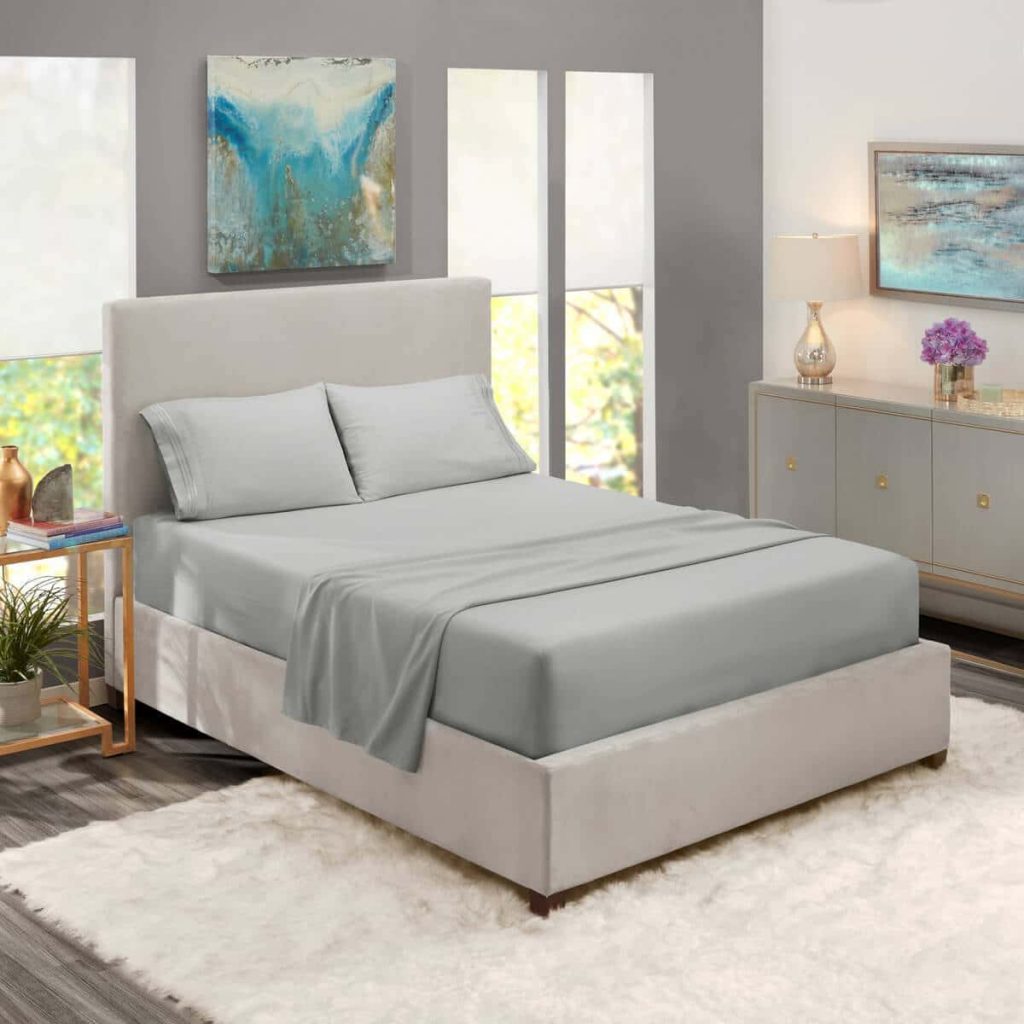 A bed with a white headboard and a blue painting on the wall
