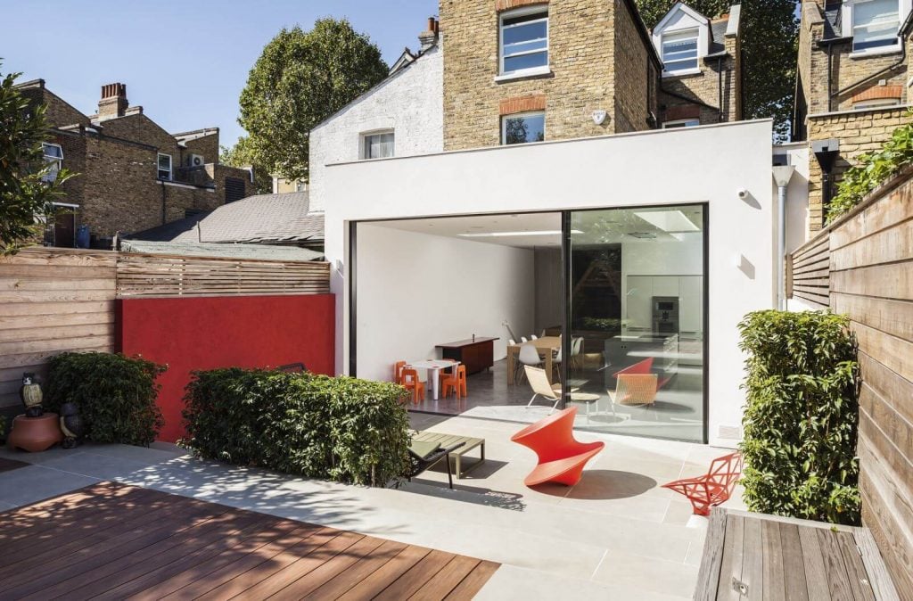 A patio with a red chair next to a red wall idea