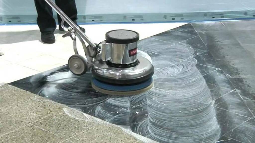 A person using a machine to paint a floor
