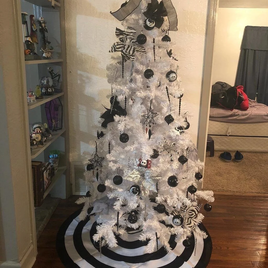 A white christmas tree decorated with black and white ornaments
