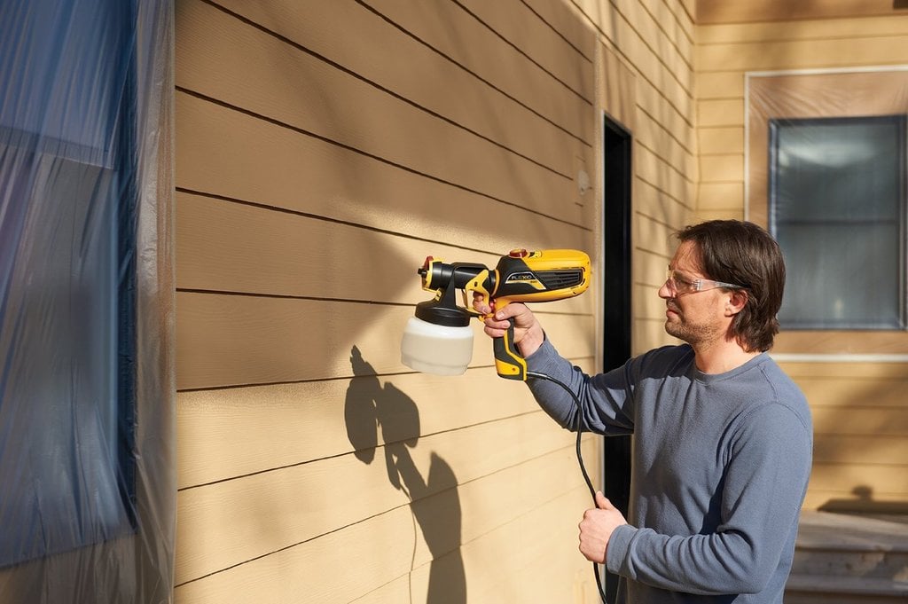 A man painting a house with a paint roller
