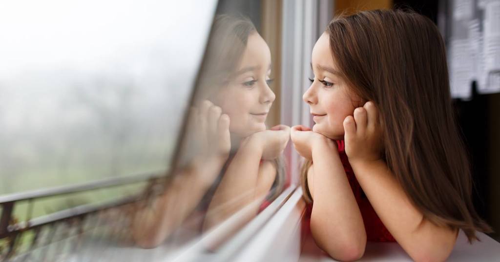 A girl looking out a window at mirror
