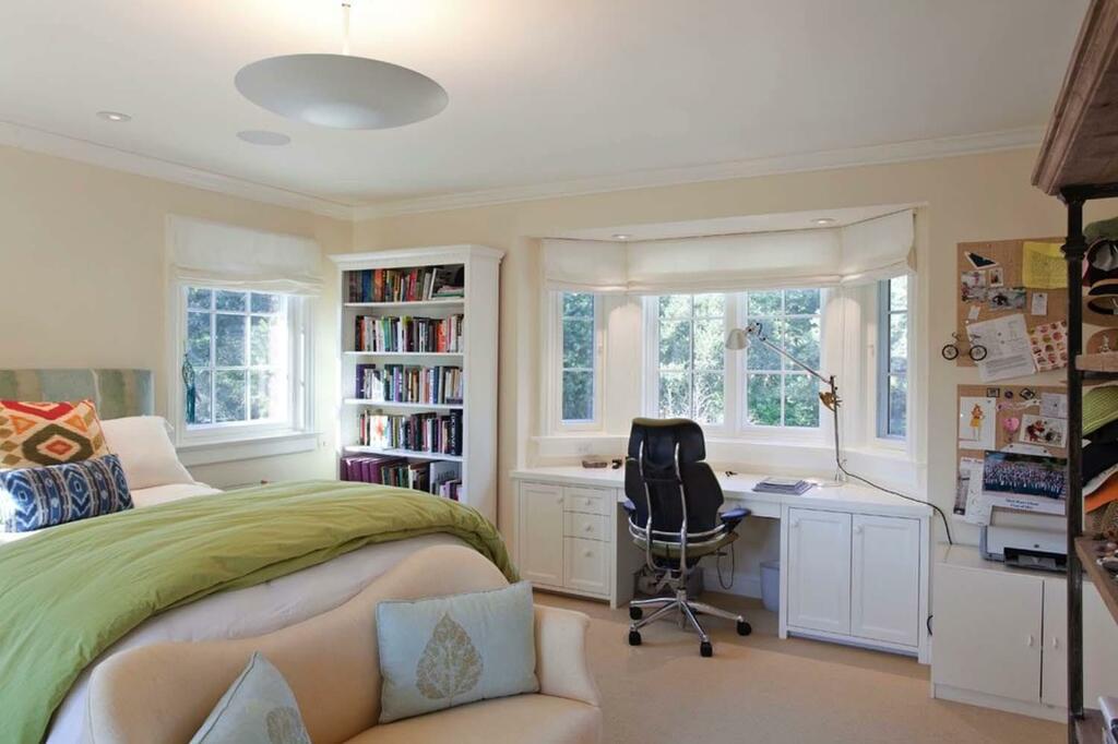 A bedroom with a bed, desk, chair and bookshelf
