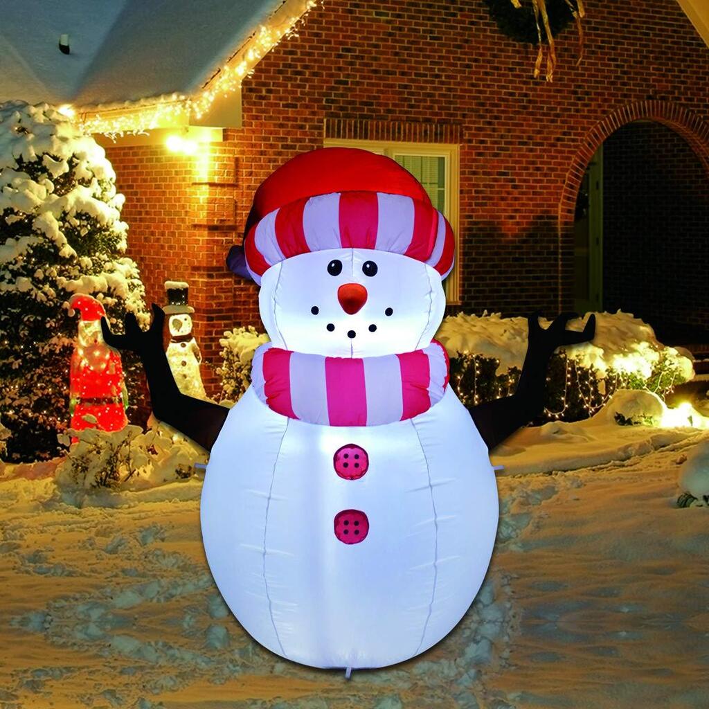 A large inflatable snowman in front of a house with red hat
