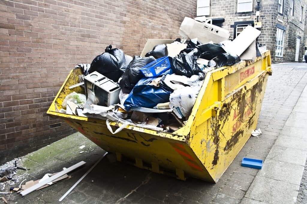 A dumpster full of trash on a city street
