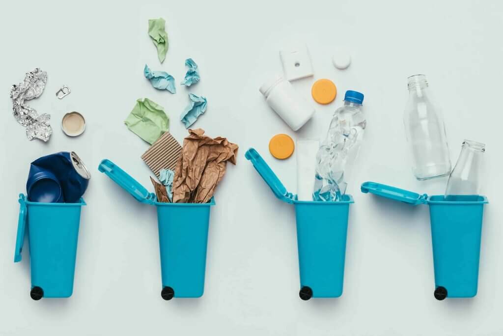 Three blue bins filled with trash and plastic bottles
