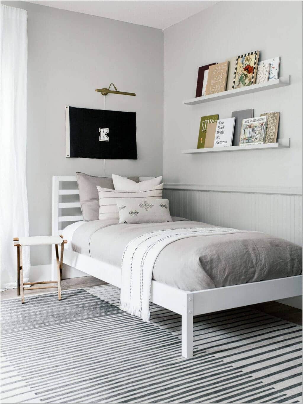 A bedroom with a white bed and a gray and white striped rug
