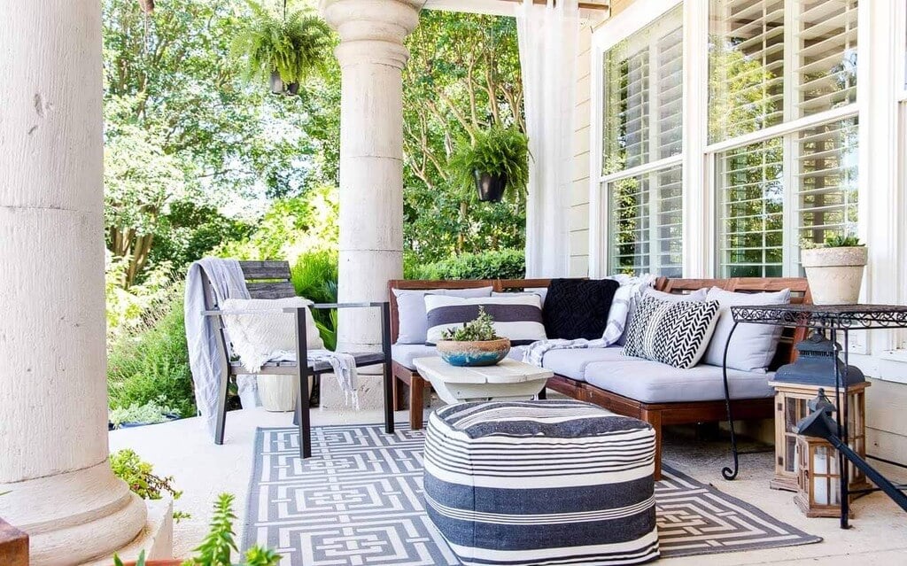 A white and black porch with furniture and potted plants.