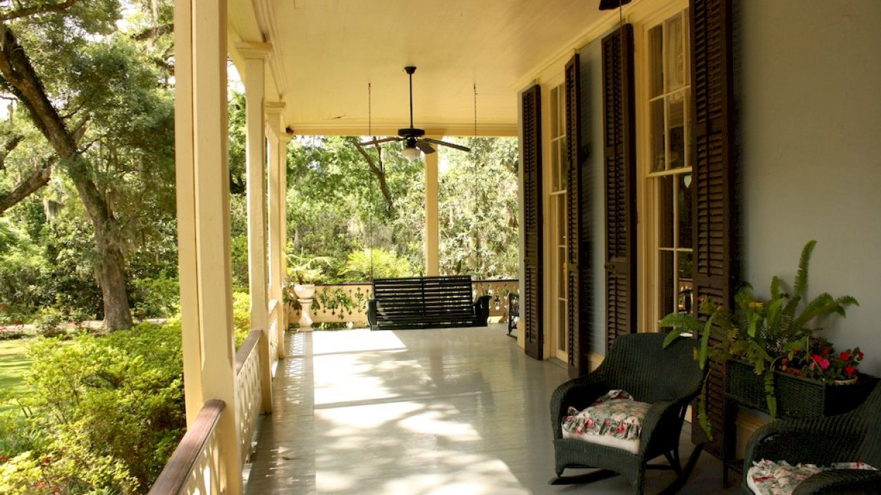 A porch with two chairs and a ceiling fan
