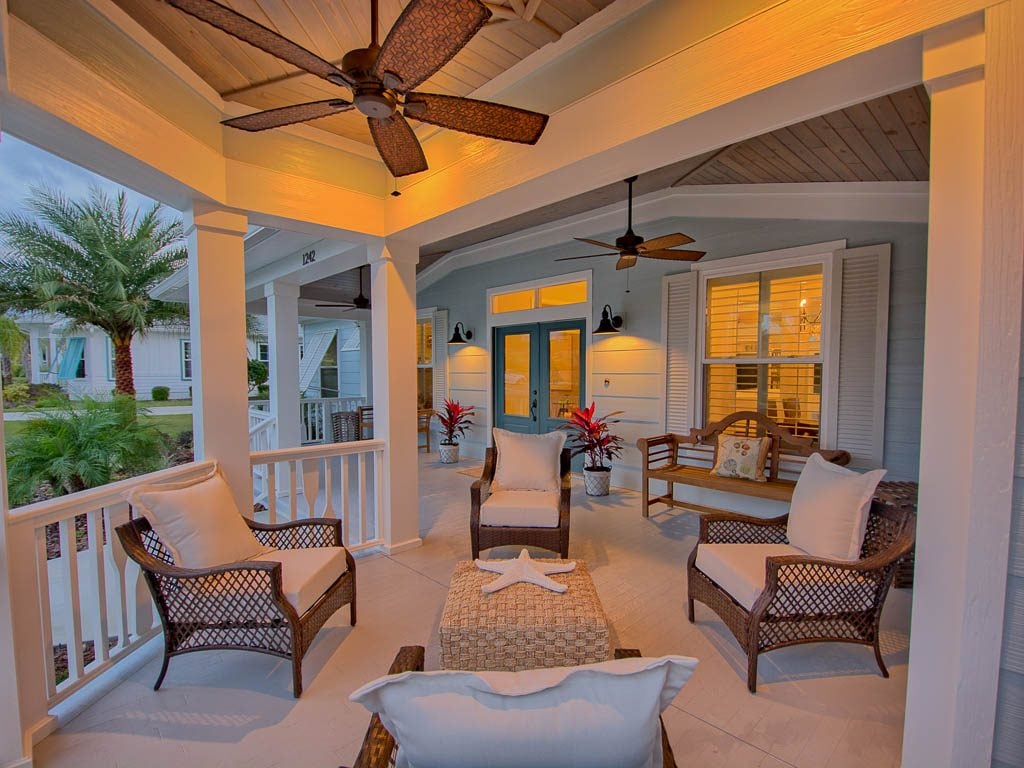 A porch with wicker furniture and a ceiling fan
