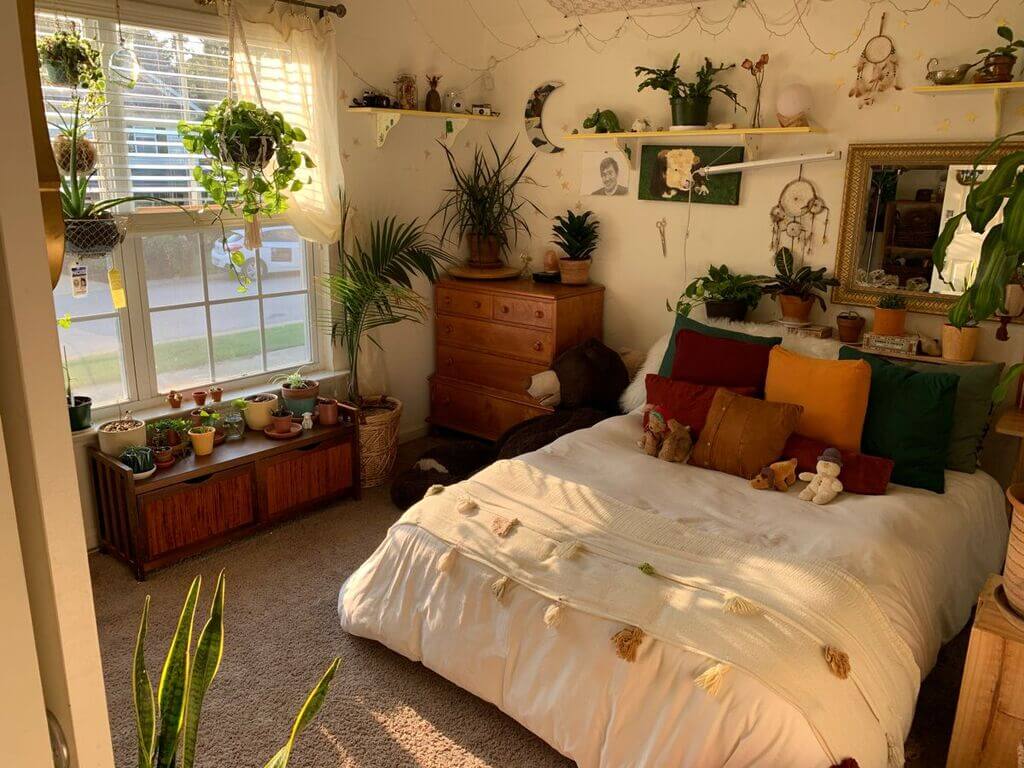 A bed room with a neatly made bed and lots of plants
