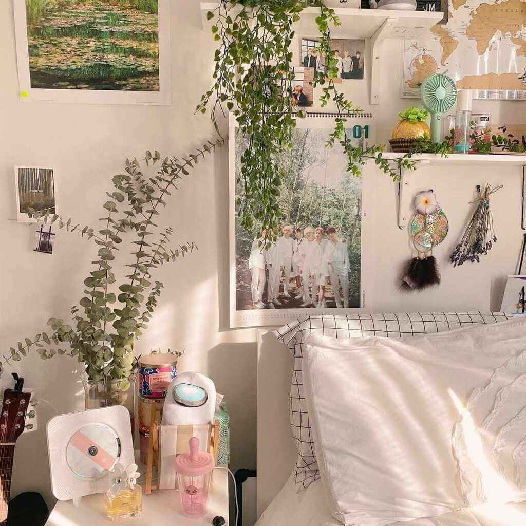 A bedroom with a bed, plants and pictures on the wall
