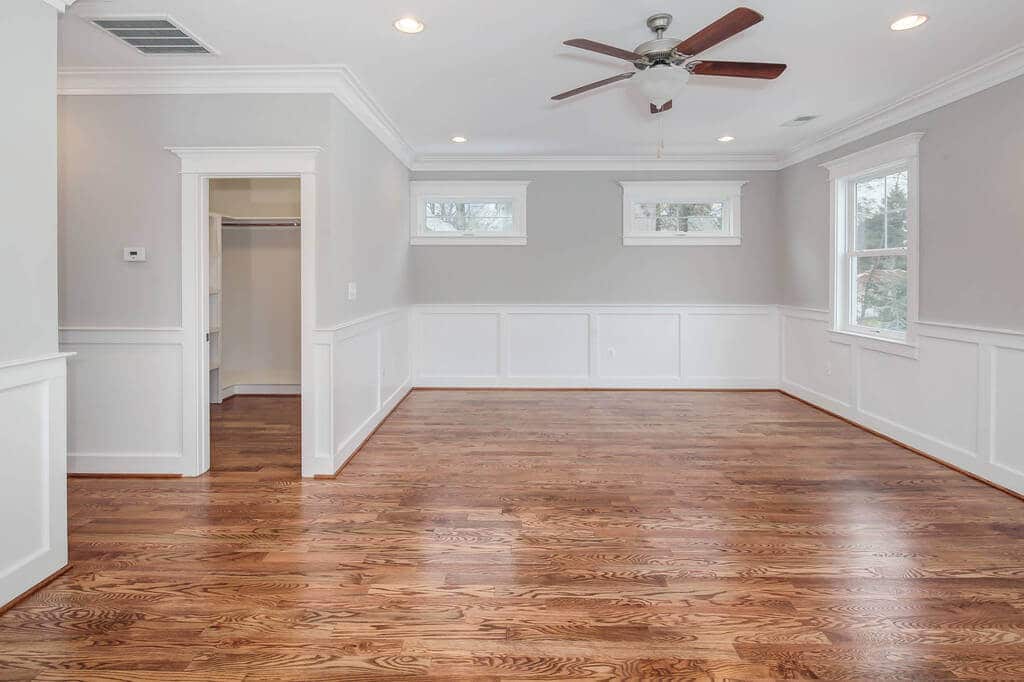 An empty room with hard wood floors and a ceiling fan
