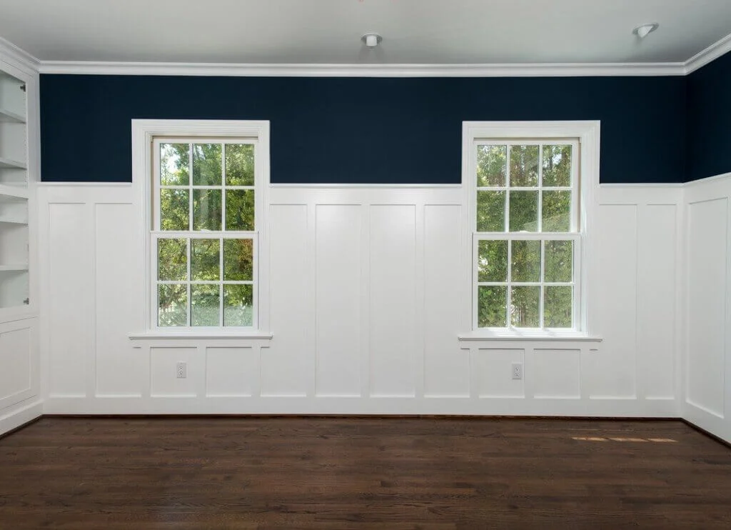 A empty room with three windows and a hard wood floor
