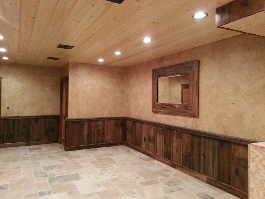 A large empty room with wood paneling and a mirror
