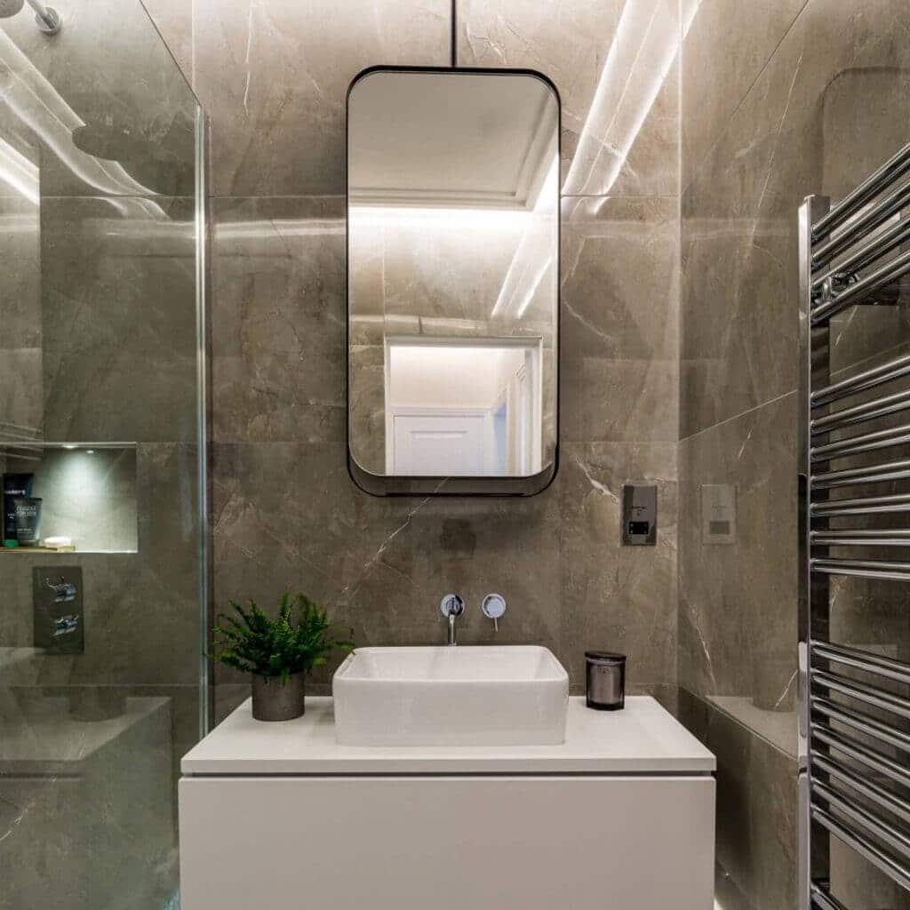A bathroom with a sink, mirror and towel rack
