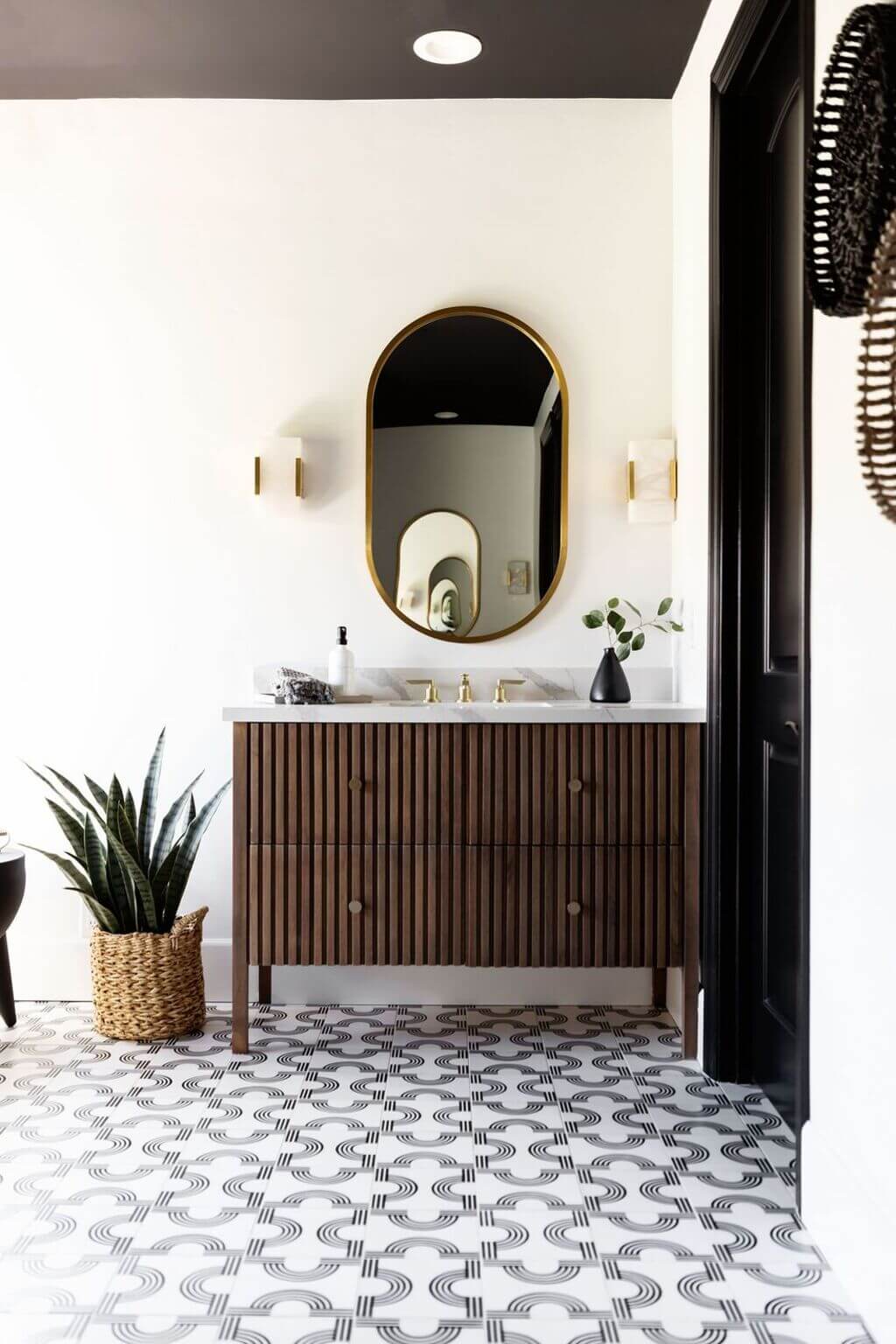 A bathroom with a sink, mirror and potted plant
